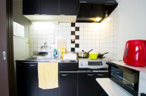 a kitchen with black cabinets and a red appliance at Sannand / Vacation STAY 2187 in Sapporo
