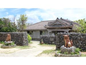 a house with two statues in front of a stone wall at HOTEL SPICE - Vacation STAY 34504v in Ishigaki Island
