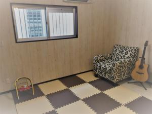 a living room with a chair and a guitar at Nago - House / Vacation STAY 76289 in Nago