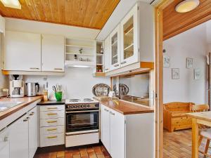 a kitchen with white cabinets and a wooden ceiling at 6 person holiday home in Farsø in Hvalpsund