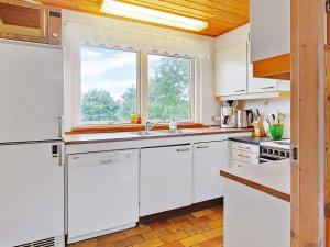 a kitchen with white cabinets and a window at 6 person holiday home in Farsø in Hvalpsund