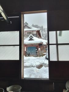 a window with a view of a house in the snow at Noukaminsyuku Zakuro no Yado / Vacation STAY 15439 in Sabae