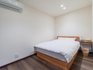 un dormitorio con una cama con sábanas blancas en Rakuten STAY HOUSE x WILL STYLE Sasebo 110, en Sasebo