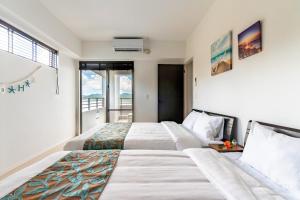 a bedroom with two beds and a balcony at Lala court seaside Yagaji / Vacation STAY 3226 in Nago