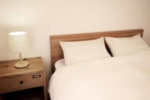 ein Bett mit weißen Laken und einer Lampe auf einem Nachttisch in der Unterkunft Rakuten STAY HOUSE x WILL STYLE Fujiyoshida Matsuyama 102 in Fujiyoshida