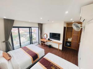 a hotel room with two beds and a television at Vươn Ra Biển Lớn Hotel in Cẩm Xuyên
