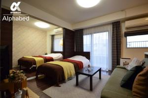 ein Hotelzimmer mit zwei Betten und einer Couch in der Unterkunft Alphabed TakamatsuFurujinmachi 902 / Vacation STAY 21916 in Takamatsu