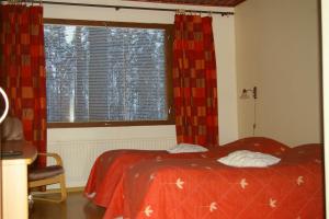 a bedroom with a bed with a red comforter and a window at Karjalan Kievari in Kesälahti