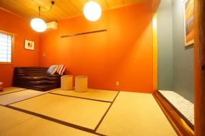 a living room with orange walls and a leather couch at Takayama - House / Vacation STAY 44324 in Takayama