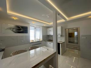 una cucina con bancone bianco e alcune sedie di Willa Apartament Prestige z sauną i siłownią na wyłączność a Żołynia Altre 50 foto