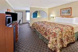um quarto de hotel com uma cama e uma televisão de ecrã plano em Americas Best Value Inn & Suites La Porte/Houston em La Porte
