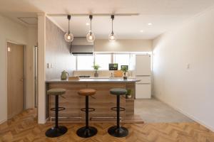 a kitchen with a counter and two bar stools at 栞-shiori-FUNAKURA in Ishigaki Island