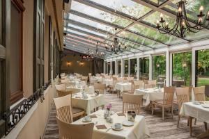 a restaurant with white tables and chairs and windows at Hotel Schwarzer Adler Tangermünde in Tangermünde