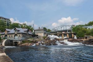a river with a bridge and a waterfall at Knights Inn Bracebridge in Bracebridge