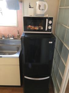un micro-ondes au-dessus d'un réfrigérateur dans une cuisine dans l'établissement Utopia Wakamiya 106 / Vacation STAY 5141, à Fukuoka