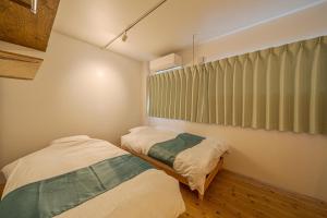 una camera da letto con due letti e un dipinto sul muro di Linden Haus BEPPU - Vacation STAY 54769 a Beppu