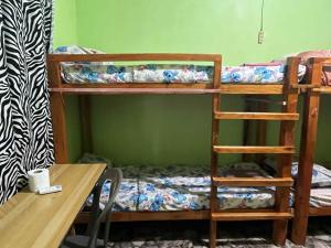 a dorm room with two bunk beds and a desk at Zia's HomestayRoom3 in Siquijor