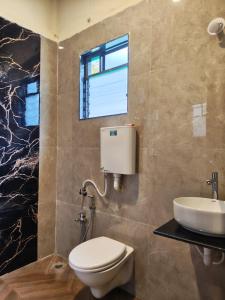 ein Badezimmer mit Toilette und Waschbecken in der Unterkunft Kalyani Village Resort in Khanivde