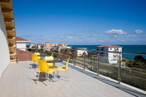 einen Balkon mit gelben Stühlen, einem Tisch und Meerblick in der Unterkunft Residence Coccinella in Torre Melissa