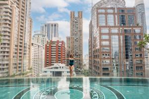 a woman standing on the edge of a swimming pool in a city at Hotel Muse Bangkok, Autograph Collection in Bangkok +218 photos