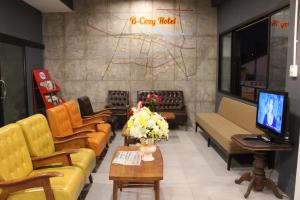 a waiting room with couches and chairs and a tv at B-Cozy Hotel in Uttaradit