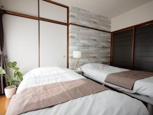 別府市にあるLiving CUBE Beppu Station / Vacation STAY 54924のレンガの壁のベッドルーム1室(ベッド2台付)