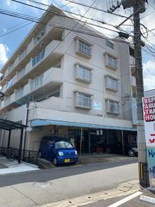 ein blauer Lieferwagen, der vor einem Gebäude geparkt ist in der Unterkunft Living CUBE Beppu Station Annex / Vacation STAY 54919 in Beppu