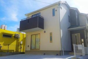 a yellow and white house with a balcony on it at 5-9-6 / Vacation STAY 59601 in Nago