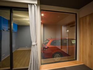 ein Spiegelbild eines roten Wagens in einem Fenster in der Unterkunft Rakuten STAY MOTEL Kujukurihama Katakai 104 2LDK with BBQ terrace Garage concept room in Kujukuri