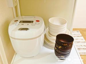 ein weißer Mischer neben einem Stapel von Platten in der Unterkunft Petit Hotel 017 / Vacation STAY 61793 in Tokushima