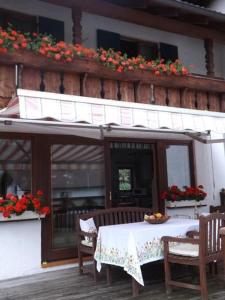 a table and chairs on a patio with flowers on a building at Abendsonne in Lechbruck