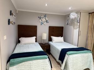 a bedroom with two beds and a clock on the wall at Nautica flat 401 in Mossel Bay +26 photos