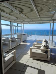 a room with white furniture and a view of the ocean at Nautica flat 401 in Mossel Bay