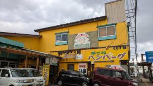 a yellow building with cars parked in front of it at Hamburger restaurant Big foot - Vacation STAY 16323 in Hachinohe