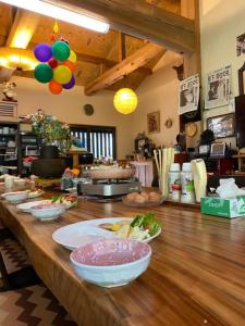 a long wooden counter with bowls of food on it at Tsugoe's House Villa / Vacation STAY 74618 in Saijo