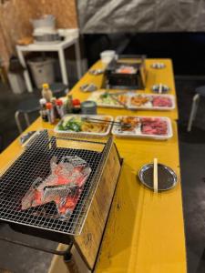 une table jaune avec de la nourriture dessus avec un gril dans l'établissement Makino Kogen 123 Building / Vacation STAY 79154, à Kaizu