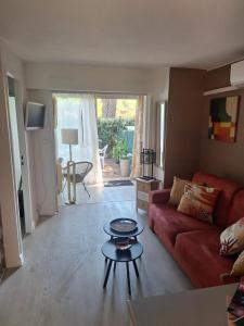 a living room with a red couch and a table at Mimilou Eleuthera 300 m centre naturiste in Cap d'Agde