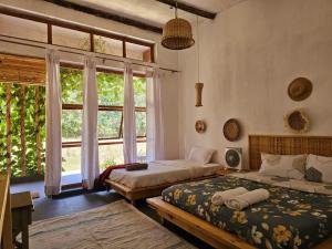 a bedroom with two beds and a large window at The River in Jinja