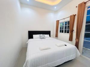 une chambre avec un grand lit blanc avec une fenêtre dans l'établissement Hatyai city habibi home 2, à Sathani Hat Yai