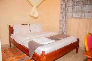 a bedroom with a bed with white sheets and a window at Villa Serene Hotel Kitale in Kitale