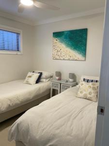 ein Schlafzimmer mit 2 Betten und ein Bild von einem Strand in der Unterkunft Patonga Street Retreat in Patonga