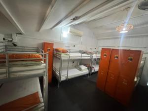 een kamer met drie stapelbedden en oranje kluisjes bij Royal Lodge @ Pagoda Street in Singapore