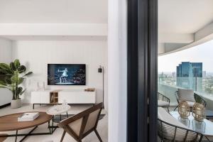 a living room with a television and a table and chairs at Prestige & Sea View 1BR with Parking TLV By Barnes in Tel Aviv
