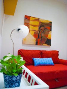 a red couch in a living room with a plant at Fausto's House in Siracusa