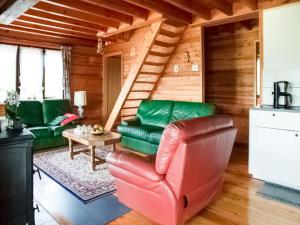 a living room with green leather furniture in a log cabin at Peaceful Retreat with Sauna in Fraiture
