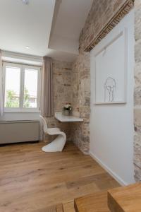 Habitación con pared de piedra y silla blanca. en Bifora Heritage Hotel en Trogir