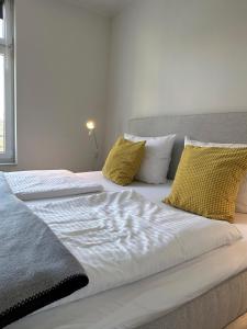 a white bed with yellow pillows in a bedroom at Rodehuus Wohnung 5 in Borkum