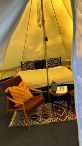 ein Schlafzimmer mit einem Bett und einem Stuhl in einem Zelt in der Unterkunft Glamping Hive by Stream 