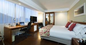 a hotel room with a bed and a desk with a computer at Quality Porto Alegre in Porto Alegre