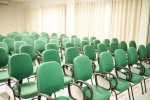 an empty room with green chairs and curtains at Italian Palace Hotel in Palmas